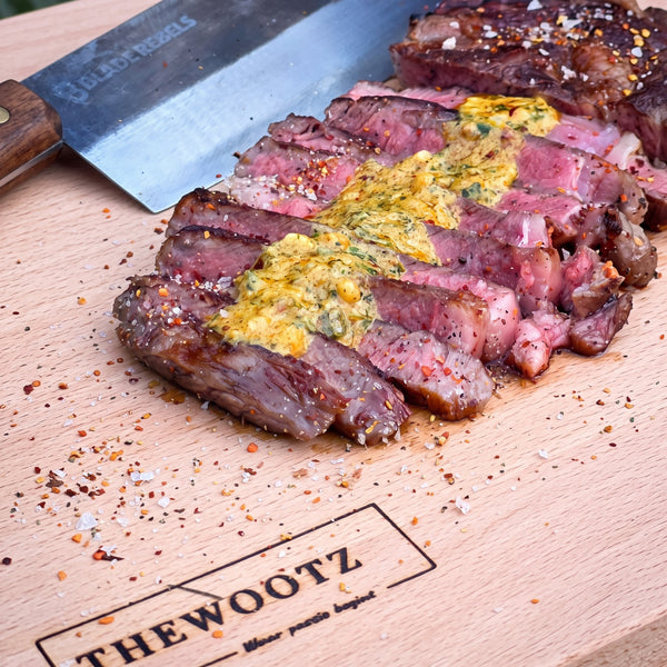 Sliced steak with herb butter on a wooden board with burned-in TheWootz logo