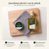 Houten snijplank met druivenpitolie, een blikje bijenwas en een grijze microvezeldoek voor onderhoud.