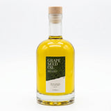 Fles met heldere druivenpitolie en een groen label met de tekst 'GRAPE SEED OIL' en 'THEWOOTZ'.