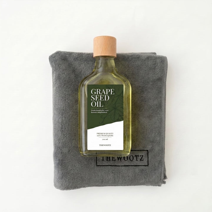 Fles druivenpitolie met houten dop op een grijs microvezeldoek. Label: GRAPE SEED OIL.
