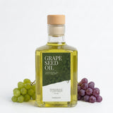 Fles druivenpitolie van TheWootz met groen label, naast groene en paarse druiventrossen.